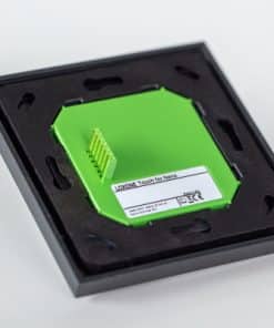 Auf der Rückseite des Loxone Touch for Nano Anthrazit ist das grüne Gehäuse in einer schwarzen Montageplatte verbaut, auf dem die Anschlusskontakte und ein Etikett mit technischen Angaben sichtbar sind.